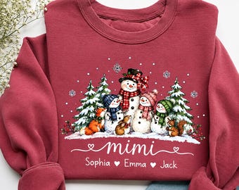 May include: A maroon long-sleeve sweatshirt featuring a graphic of four snowmen and forest animals in a snowy landscape. The text "mimi" is printed in white script above the names "Sophia", "Emma", and "Jack" separated by white heart icons.