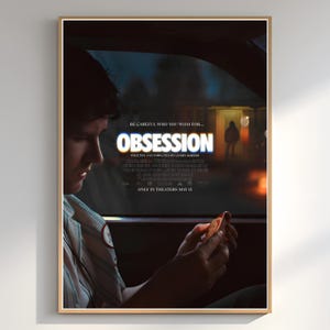 May include: A framed movie poster for "Obsession" with a man in a car. The poster has the title "Obsession" in large, illuminated letters. The text "Be careful who you wish for..." is above the title. The release date is May 15.