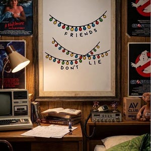 May include: A framed print with the words "FRIENDS DON'T LIE" in black text, decorated with colorful string lights. The room features vintage movie posters, a desk with books, and a retro computer, creating a nostalgic atmosphere.