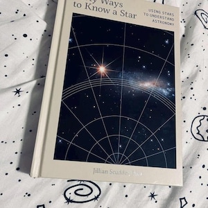 May include: A book titled "Forty Ways to Know a Star" with a dark blue cover showing a star chart and a galaxy. The subtitle reads "Using Stars to Understand Astronomy". The author's name is Jillian Scudder.