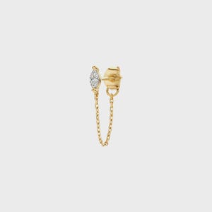 May include: A gold stud earring featuring a marquise-cut clear gemstone set in a gold frame, connected by a delicate gold chain to a small gold circular backing. The design creates a looped effect, showcasing polished metal and a faceted stone.
