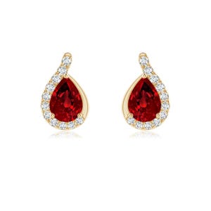 May include: A pair of gold earrings featuring a central pear-shaped red gemstone surrounded by a halo of small, clear, round-cut white stones. The design includes a tapered top section that connects to the main teardrop-shaped setting.