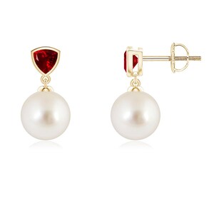Puede incluir: Un par de pendientes de oro amarillo con una piedra preciosa roja triangular en la parte superior, conectada a una perla esférica blanca colgante. Los pendientes incluyen un cierre de presión para una fijación segura y un diseño clásico.