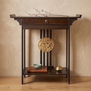 Puede incluir: Mesa consola de madera marrón oscuro con un cajón y un estante inferior. La mesa presenta una escultura de dragón circular dorada y un pequeño cuenco azul claro. Una ramita de flores descansa encima.