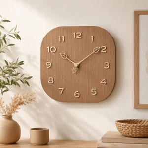 May include: A square wooden wall clock with rounded corners. The clock face is a light brown color with raised, light-colored numerals and leaf-shaped accents. The clock hands are also light-colored.