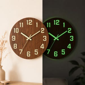 Pode incluir: Um relógio de parede redondo de madeira com acabamento castanho. O relógio apresenta algarismos e ponteiros brancos, com um efeito verde brilhante no escuro. É um item decorativo para decoração de casa.