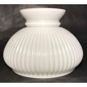 May include: A white, ribbed glass lampshade with a rounded bottom and a flared top. The shade has a classic, vintage design, perfect for a table lamp or ceiling fixture. The glass has a glossy finish.