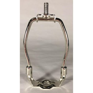 May include: A polished chrome lamp harp with a threaded top and a curved, rectangular design. The harp has a metal base with a circular opening and is designed to hold a lampshade. The lamp harp is a lighting accessory.