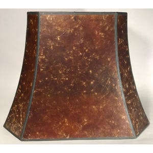 May include: A bell-shaped lamp shade featuring a dark brown, mottled, and textured surface with lighter tan, scratch-like markings throughout. The shade has a structured, flared silhouette with dark grey trim along the edges and corners.