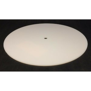 May include: A circular, flat, off-white disc with a smooth, matte surface and a single, small, centered circular hole. The object is presented as a simple, geometric shape with uniform coloring and a clean, consistent edge profile throughout.