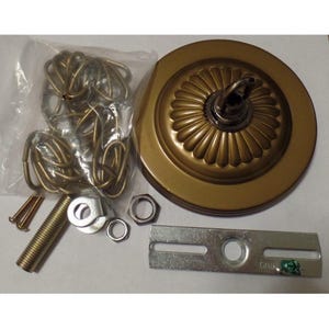 May include: A round, antique brass-colored ceiling canopy with a fluted design, accompanied by a clear plastic bag containing a brass-toned metal chain, a threaded pipe, two silver-colored nuts, two small screws, and a silver metal mounting bracket.