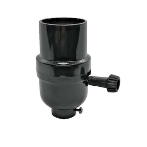 Könnte beinhalten: Eine schwarze Lampenfassung mit einem zylindrischen Oberteil, einem breiteren Mittelgehäuse und einem kleinen seitlichen Drehknopf zur Bedienung. Eine einzelne Metallschraube ist nahe der Basis der Fassung für die Glühbirnenmontage sichtbar.