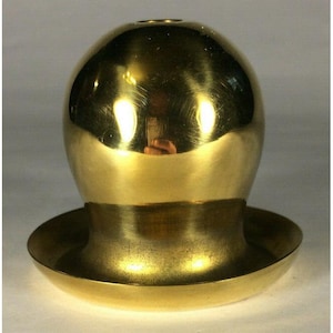 May include: A polished brass object with a smooth, rounded dome-shaped top and a wide, flat circular base. The metallic surface is reflective, showing light highlights and a subtle golden tone throughout the entire structure of the piece.