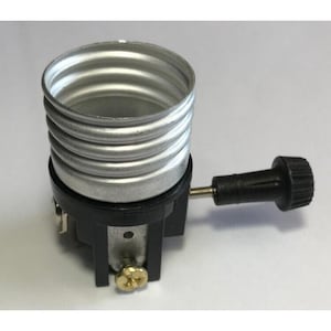 May include: A silver-coloured metal light bulb socket with a threaded interior, mounted on a black plastic base. A black plastic turn-knob switch extends from the side, and a small brass-coloured screw is visible at the bottom of the assembly.