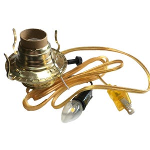 May include: A gold-toned metal lamp socket assembly featuring three curved shade support arms, a black rotary switch, and a clear power cord with a yellow two-prong electrical plug. A small clear light bulb is attached to the cord assembly.
