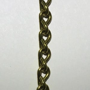 May include: A close-up of a gold-colored chain. The chain links are oval-shaped and interlocked, creating a continuous pattern. The chain is likely used for jewelry or as a decorative element.