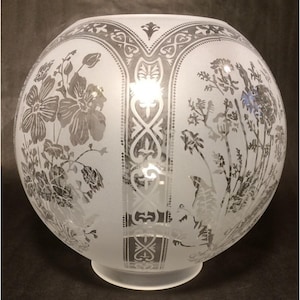 May include: A spherical frosted glass lamp shade featuring etched floral patterns and vertical decorative bands. The design includes detailed illustrations of various flowers and foliage, with a clear circular opening at the top and base.