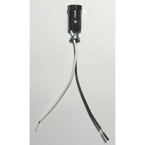 Op de afbeelding: Een zwarte cilindrische fitting met een zilverkleurige metalen ring aan de basis. Twee geïsoleerde elektriciteitsdraden, één wit en één zwart, lopen naar beneden vanuit de fitting, elk met een klein stukje blootliggende koperdraad aan het uiteinde.