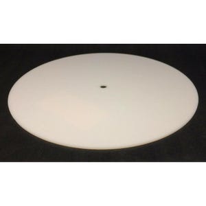 May include: A flat, circular, white disc with a smooth, matte surface and a single, small, centered hole. The object is perfectly round and uniform in color, presenting a clean, simple geometric shape without any additional markings or textures.