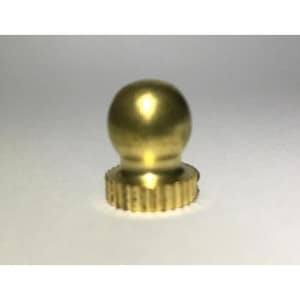 May include: A small, metallic gold-colored finial featuring a smooth, spherical top section that transitions into a cylindrical base with a vertically ribbed, textured edge. The object has a polished finish that reflects light on its rounded surface.