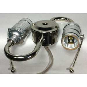 May include: A polished nickel dual-socket light fixture component featuring a central circular mounting base, two curved arms extending outward, and two light bulb sockets each equipped with a silver metal pull chain for manual operation.