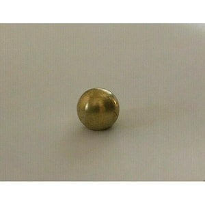 May include: A small, solid brass sphere with a polished, reflective surface. The ball is a warm gold color and sits on a neutral background. The sphere is a simple, round shape.