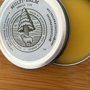 May include: A silver tin of Multi-Balm Vanilla, 2 oz, with a partially open lid revealing a yellow balm. The label features a tree and sheep graphic, with text including "Made by Bartenders, For The World!" and "Full Circle Nature's Products".
