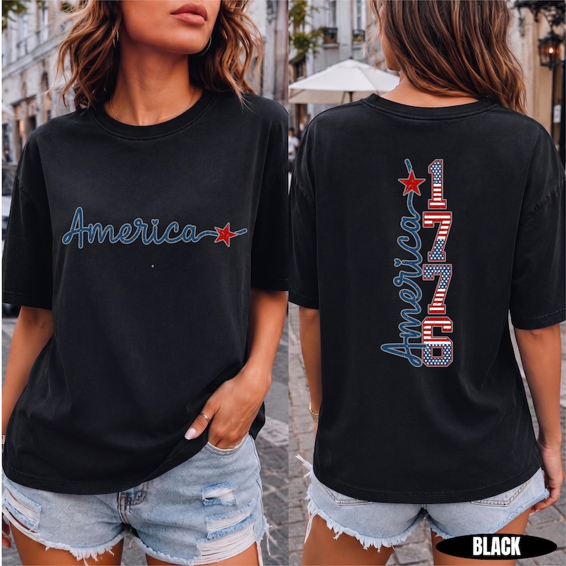 May include: A black short-sleeve t-shirt featuring the word America in blue script with a red star on the front. The back displays the word America vertically next to the number 1776, styled with red, white, and blue American flag patterns.
