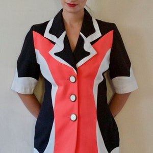 以下が含まれることがあります： 黒、白、コーラルのカラーブロックブレザー。 ブレザーは半袖で、白いボタンが3つ付いています。 デザインはVネックで、さまざまな場面に適したテーラードフィットです。