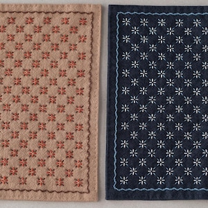 Peut inclure: Deux dessous de verre rectangulaires brodés. L'un est beige avec un motif répété de motifs floraux rouges. L'autre est bleu marine avec un motif floral blanc et une bordure cousue bleue. Les deux ont un aspect texturé.