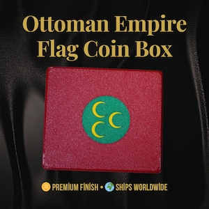 May include: A red coin box with the text "Ottoman Empire Flag Coin Box" in gold lettering. The box features a green circle with three yellow crescent moons. The box has a premium finish.