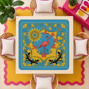 May include: A square table with a light wood frame featuring a vibrant blue and yellow surface design. The illustration depicts a central pink heron, a starfish with multiple eyes, flying fish, a compass sun, and two black lizards among ginkgo leaves.