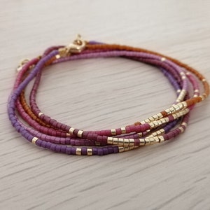 Puede incluir: Varios brazaletes de cuentas en tonos morado, rosa y marr&oacute;n, con detalles dorados. Los brazaletes son en capas y est&aacute;n hechos de peque&ntilde;as cuentas cuadradas. La imagen incluye etiquetas de texto: #4, #14, #15, #22 y #24.