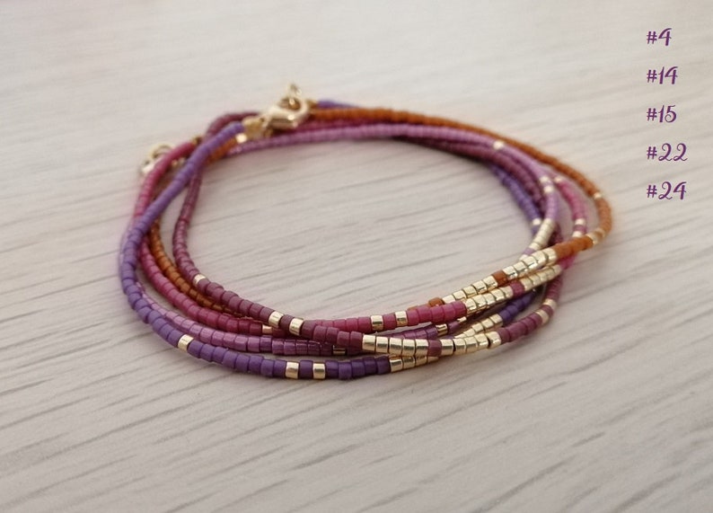 Puede incluir: Varios brazaletes de cuentas en tonos morado, rosa y marr&oacute;n, con detalles dorados. Los brazaletes son en capas y est&aacute;n hechos de peque&ntilde;as cuentas cuadradas. La imagen incluye etiquetas de texto: #4, #14, #15, #22 y #24.