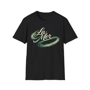 Könnte beinhalten: Schwarzes T-Shirt mit dem Schriftzug "La Mer" in geschwungener Schrift. Das Design beinhaltet eine wirbelnde, abstrakte Grafik in Grün- und Blautönen, die das Meer darstellt.
