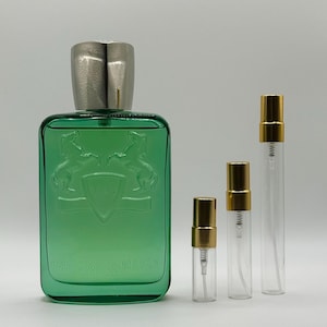 May include: A green rectangular perfume bottle with a silver cap and three smaller glass spray bottles with gold caps. The perfume bottle has a crest design and the words "PARFUMS de MARLY PARIS".
