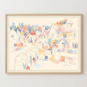 May include: A framed art print featuring a sketch of a village scene with a stone bridge over a stream, houses with pitched roofs, and trees. The illustration uses a palette of soft peach, blue, yellow, and red lines on a cream background.