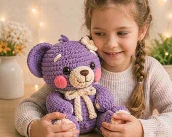 Lila virkad nallebjörn i presentask med flicka som använder laptop Amigurumi-mönsterdisplay och mysig hantverksstil