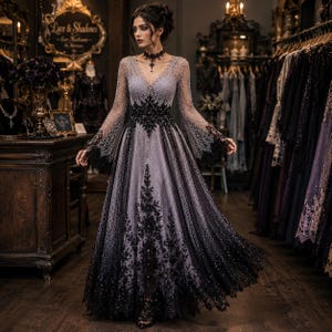 Peut inclure: Une robe longue au sol avec une base lavande et des superpositions de dentelle noire complexe, des manches longues évasées, un décolleté en V profond et un corsage ajusté. La jupe présente un dégradé avec une broderie florale noire dense.