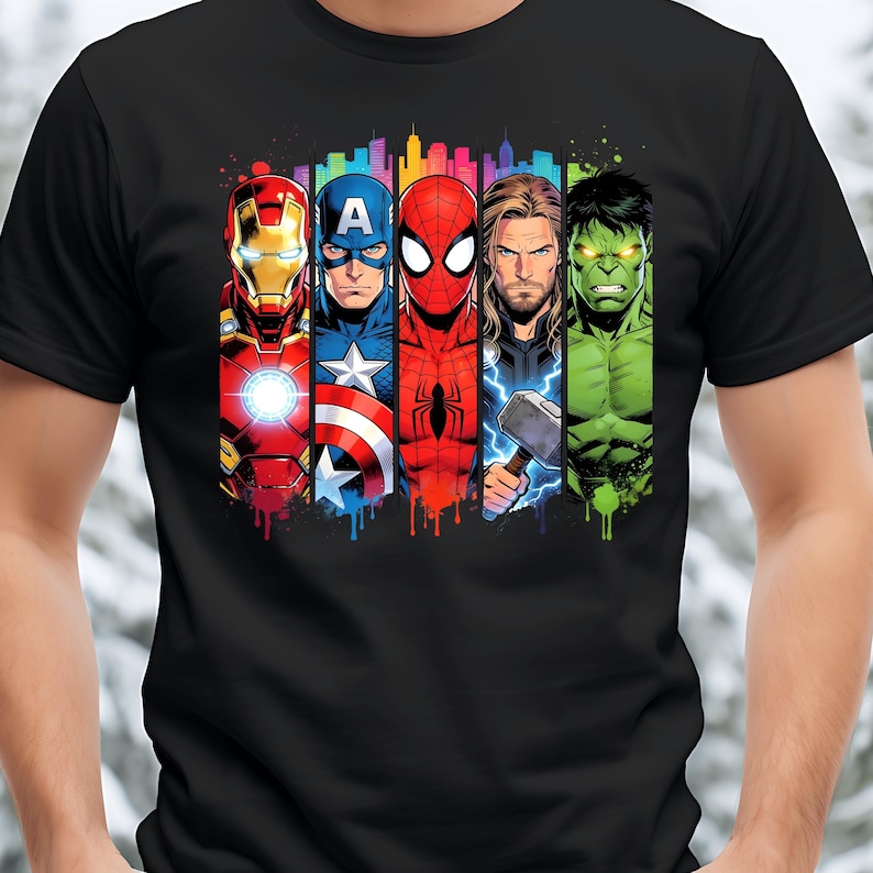 Op de afbeelding: Zwart t-shirt met een kleurrijke afbeelding van Iron Man, Captain America, Spider-Man, Thor en de Hulk. Het ontwerp bevat een stadsgezicht en verfdruppeleffecten, met de iconische Marvel-superhelden.