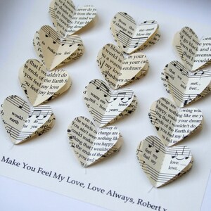 May include: A garland of paper hearts made from music sheets with the text "Make You Feel My Love, Love Always, Robert" at the bottom.