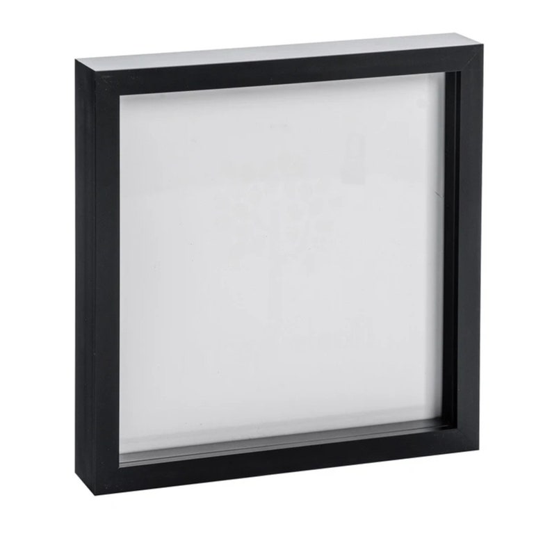 May include: A black square picture frame with a white mat. The frame is made of wood and has a simple design.