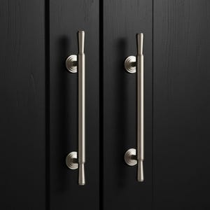 May include: Two vertical brushed nickel cabinet pulls with a cylindrical bar design and tapered ends. Each handle is mounted to a black cabinet door with two circular bases, featuring a smooth metallic finish and a clean, streamlined appearance.