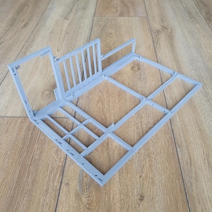 May include: A light gray, 3D-printed structure with a rectangular base and a railing. The design features multiple geometric shapes and a grid-like pattern. The object is made of plastic and appears to be a component of a larger structure.