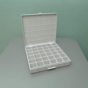 Op de afbeelding: Een witte plastic opbergdoos met een open scharnierend deksel met een rasterpatroon. De binnenkant bevat een vast tussenschotsysteem dat zesendertig individuele vierkante vakjes creëert, gerangschikt in een raster van zes bij zes.