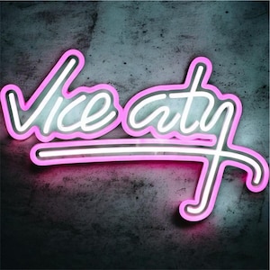 Peut inclure: Une enseigne au néon affichant les mots Vice City dans une police d'écriture cursive. Le lettrage présente une lumière intérieure blanche vive entourée d'une bordure rose éclatante, créant un effet superposé sur le fond texturé.