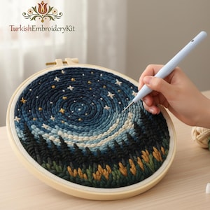 May include: An embroidery hoop with a night sky design, including a swirling galaxy and forest silhouette. The text "TurkishEmbroideryKit" is visible. A light blue punch needle is used to create the textured artwork.