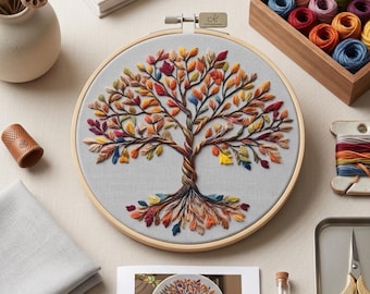 May include: A circular wooden embroidery hoop containing light gray fabric with a hand-stitched tree design. The tree features a twisted trunk and branches adorned with multicolored leaves in shades of red, orange, yellow, blue, and purple.