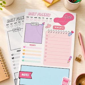 Puede incluir: Dos hojas de planificador diario con secciones para fecha, objetivos, prioridades, lista de tareas y notas. Los diseños incluyen colores pastel, iconos de corazones e ilustraciones de una chincheta, clip, lápiz y taza de café con el texto DAILY PLANNER.