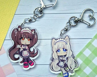 Könnte beinhalten: Zwei Acryl-Schlüsselanhänger mit Chibi-Figuren mit Katzenohren in Dienstmädchen-Outfits. Eine Figur hat braunes Haar und orangefarbene Augen, die andere weißes Haar und blaue Augen. Beide Anhänger haben herzförmige Karabinerverschlüsse aus Metall.